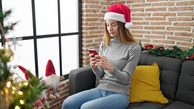 Kafkasyalı genç bir kadın akıllı telefon kullanarak Noel 'i evde kutluyor.