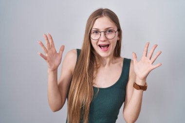 Beyaz arka planda duran genç beyaz kadın çılgın ve başarıyı kollarını kaldırıp heyecanla haykırarak kutluyor. Kazanan konsept 