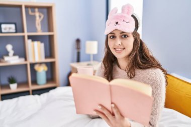 Genç, güzel İspanyol kadın kitap okuyor. Yatak odasında kahve içiyor.