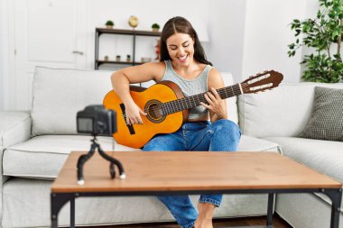 Evinde klasik gitar çalan genç ve güzel bir İspanyol kadın.