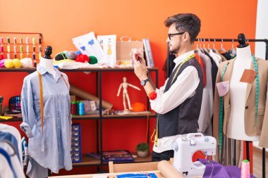 Genç İspanyol terzi atölyeden gömleğe akıllı telefondan fotoğraf çekiyor.