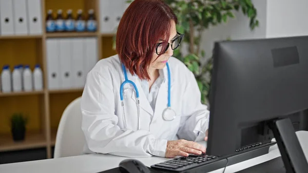Middle age woman doctor using computer working at the clinic