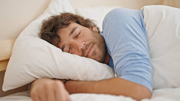 Young hispanic man lying on bed sleeping at bedroom