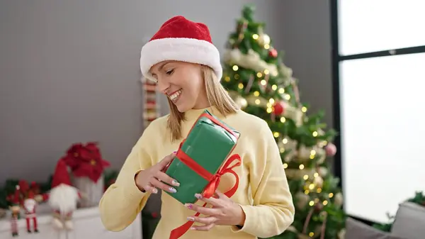 年轻的金发女人拿着礼物站在家里的圣诞树旁 — 图库照片