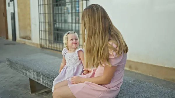 白种人的母亲和女儿 看上去自信而快乐 一起坐在户外的城市长椅上 在他们的关系中流露出快乐 享受着一段有趣的时光 — 图库照片