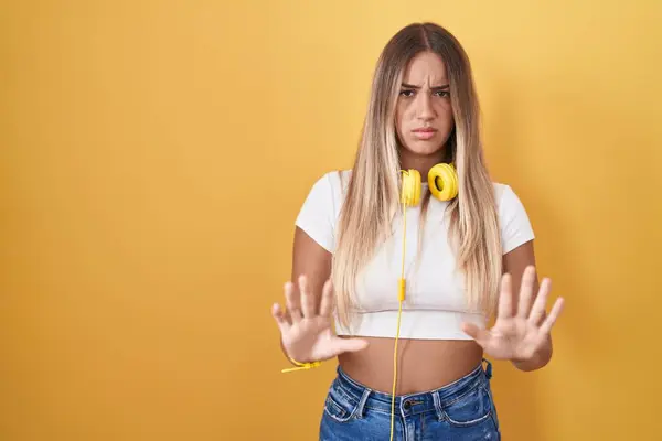Mujer Rubia Joven Pie Sobre Fondo Amarillo Con Auriculares Alejando — Foto de Stock