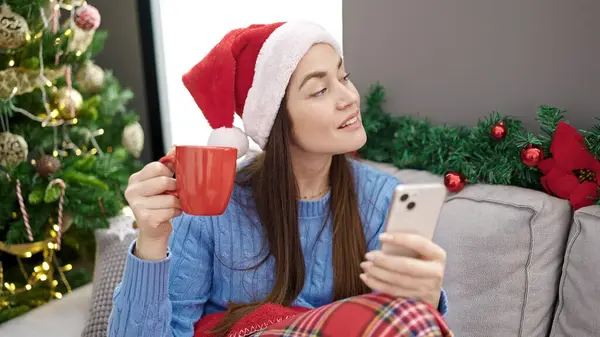 年轻的高加索女人在家里用智能手机喝咖啡庆祝圣诞节 — 图库照片