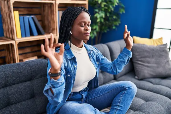 African american woman doing yoga exercise sitting on sofa at home