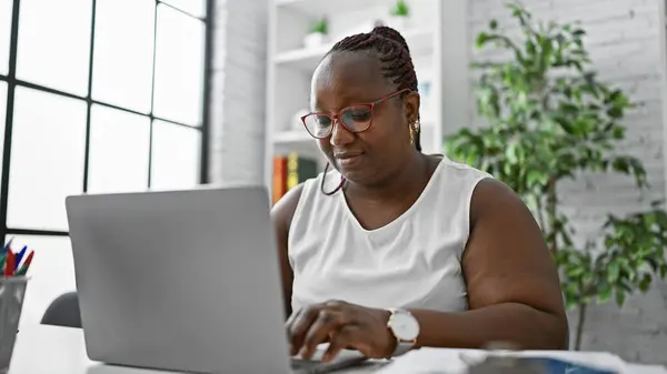 以非洲裔美国女工为重点 擅长经商 这位老板女士在她的笔记本电脑上勤勤恳恳地工作 体现了她办公室的成功和专业精神 — 图库照片