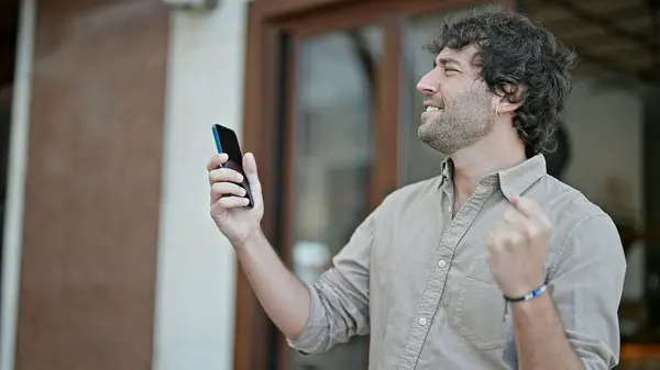 Junger Hispanischer Mann Lächelt Selbstbewusst Mit Smartphone Und Siegergeste Auf — Stockfoto
