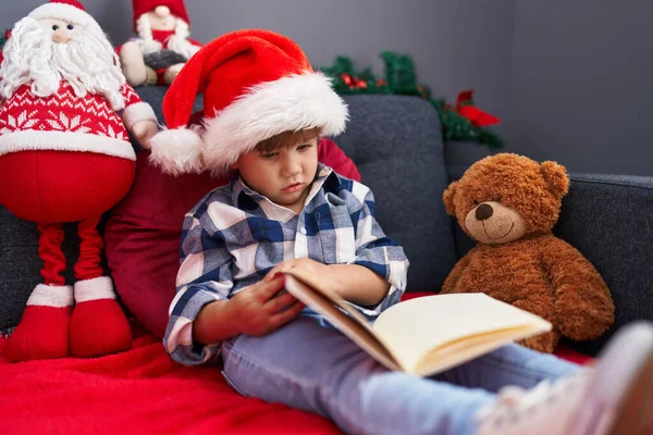Uroczy Latynoski Chłopiec Czyta Książkę Siedząc Kanapie Przez Świąteczne Dekoracje — Zdjęcie stockowe