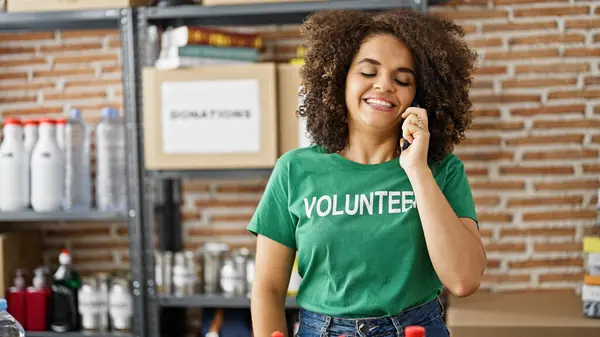 Young Beautiful Hispanic Woman Volunteer Talking Smartphone Smiling Charity Center — Stock Photo, Image