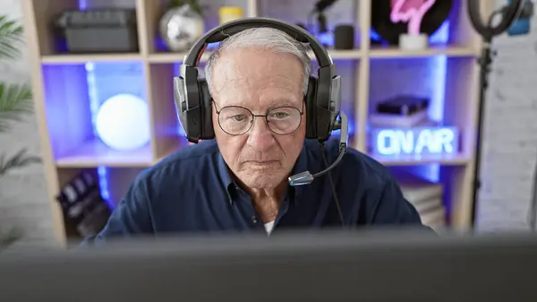 Internet savvy senior man streamer, a relaxed game night indoors, rocking his headset while immersed in a futuristic virtual video game, streaming live from his gaming room