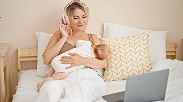 Mãe Filha Sentadas Cama Amamentando Bebê Ouvindo Música Quarto — Fotografia de Stock