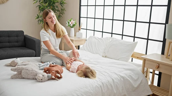 Caucasian mother and daughter tickle-fest! a heartwarming scene of laughter in the bedroom, lying on the bed, sharing a lot of giggles