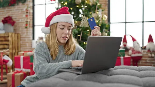 Young blonde woman shopping laptop and credit card celebrating christmas at home