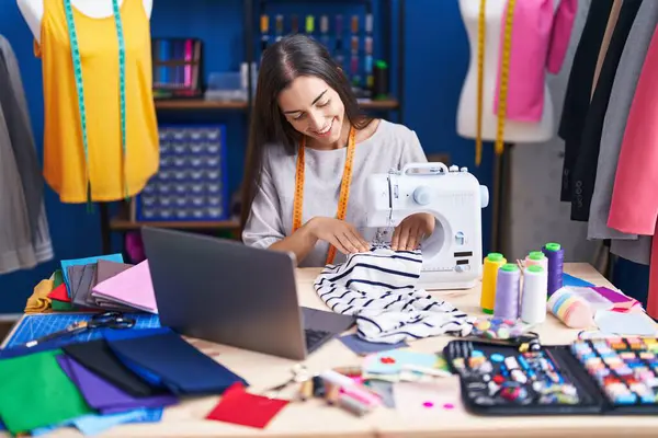 服装厂用缝纫机和笔记本电脑裁缝店的年轻漂亮女裁缝 — 图库照片