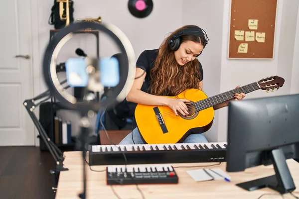 Young beautiful hispanic woman musician having online classical guitar class at music studio