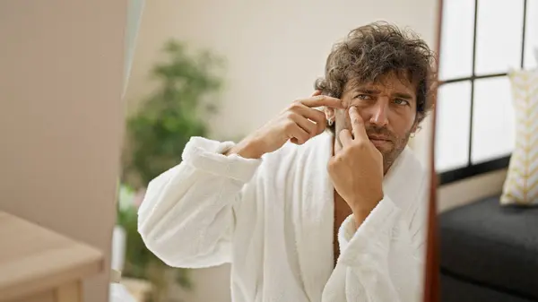 Young Hispanic Man Wearing Bathrobe Popping Pimple Looking Mirror Home — Stock Photo, Image