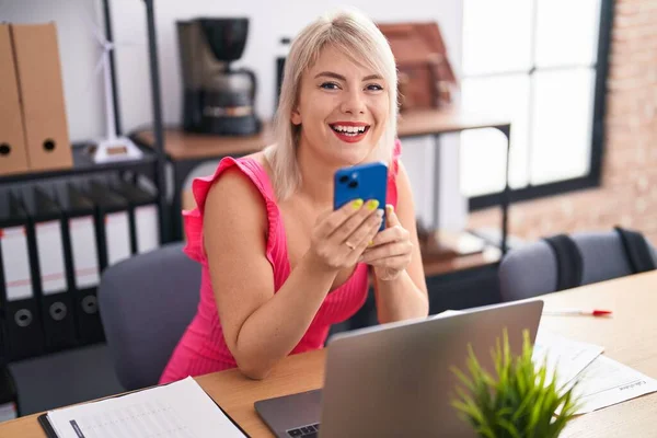 Young blonde woman business worker using laptop and smartphone at office