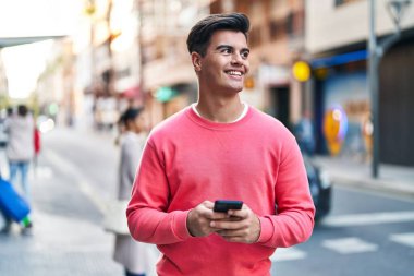 Sokakta akıllı telefon kullanan, kendine güvenen genç bir İspanyol.