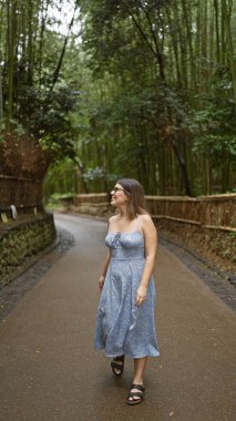 Gözlüklü güzel İspanyol kadın, Kyoto 'nun yemyeşil bambu ormanlarının arasında durup etrafa bakıyor, neşe ve şaşkınlık içinde..