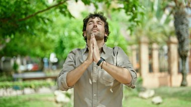 Genç İspanyol adam parkta yoga egzersizi yapıyor.