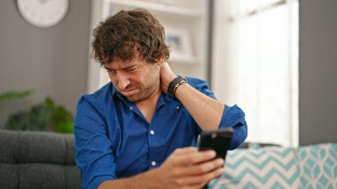 Genç İspanyol adam evde rahim ağrısı için akıllı telefon kullanıyor.