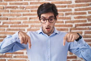 Duvarın arkasında dikilen İspanyol genç adam parmaklarını göstererek reklamını yapıyor, şaşırmış yüz ve ağzını açıyor. 