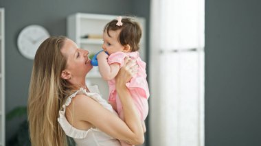 Anne ve kızı evde oyuncak emerek birbirlerine sarılıyorlar.