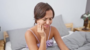 Pijamalı, genç, güzel İspanyol bir kadın yatakta acı içinde oturuyor, ağzı açık, diş ağrısından kıvranıyor. Yatak odası diş hastalığından dolayı beklenmedik bir dişçi odası haline geldi..