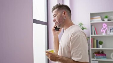 Telefonda derin bir sohbete dalmış, sabahları kahvesini yudumlarken pencereden üzgün üzgün bakışlar atan ciddi bir İspanyol genç adam..