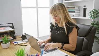 Güzel, orta yaşlı sarışın bir kadın, profesyonel bir iş adamı, ofis masasında dizüstü bilgisayarla çalışıyor ve öksürüyor - endişe verici bir hastalık belirtisi.