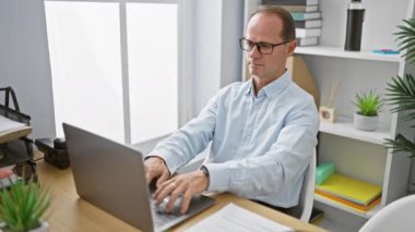 Pozitif orta yaşlı bir yönetici. Gözlüğünü çıkarıyor, kollarını uzatıyor. İşini, şık ofis masasında rahatlamak için takas ediyor..