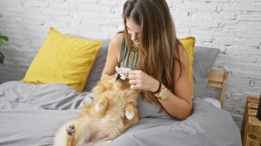 Kendinden emin, genç İspanyol bir kadın köpeğini öperken her ikisi de, pozitif bir atmosferle çevrili bir şekilde yatak odasında keyif çatıyor.