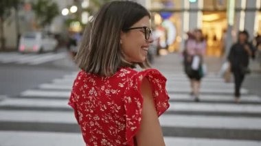 Gözlüklü çekici İspanyol kadın alışveriş merkezinde yürürken ve gülümserken kamerayı büyülüyor.