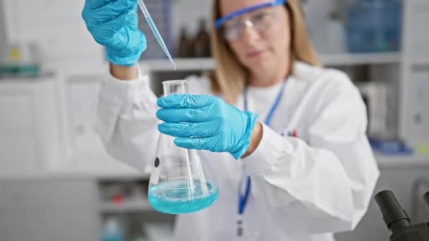 실험실에서 화려한 금발의 과학자 그녀가 측정하고 연구를위한 테스트 튜브에 액체를 — 비디오