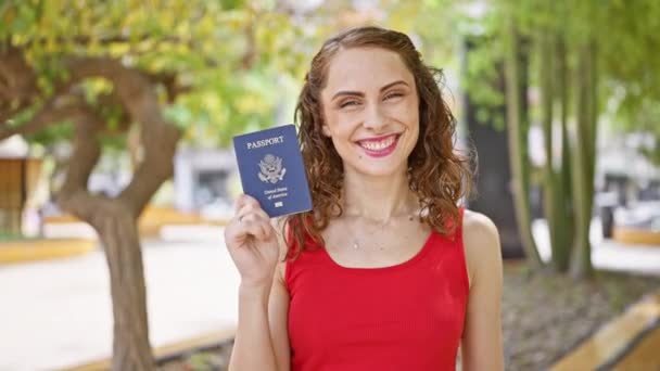 一位容光焕发的年轻女子在公园的阳光下微笑着举着她的美国护照 为即将到来的令人兴奋的旅行活动献上了她的大拇指 — 图库视频影像