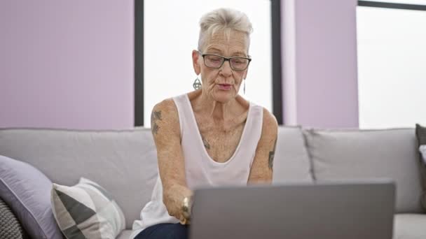 Gri Saçlı Gözlüklü Yaşlı Bir Kadın Evdeki Koltukta Otururken Konsantrasyonlu — Stok video