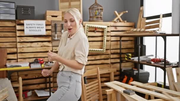 カルペントリーワークショップで喜びと踊る陽気な若いブロンドの女性大工は 業界の幸福の美しい肖像画に木工労働者の喜びを体現しています — ストック動画