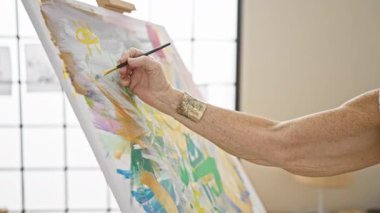 Sanat stüdyosundaki kadın ressamın elleri zarifçe tuvale resim çiziyor. Yerel akademideki olgun öğrenciler için yaratıcılık dersi.