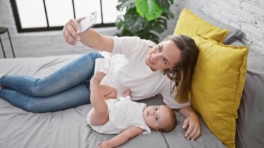 Anne ve kızının mutlu bir yaşam tarzı, evde kendine güvenle yatarken birlikte sıradan selfie çekmeleri.