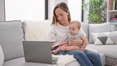 Rahat anne ve güzel kız evdeki kanepede oturuyor, dizüstü bilgisayarla online dünyayı keşfediyor, havalı, yavaş tempolu bir hayat sürüyor.