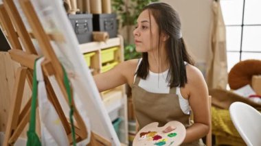 Gülümseyen genç, İspanyol bir sanatçı, güzel, kendine güvenen bir kadın sanat stüdyosunda çizim yapıyor, yaratıcı hobisinden zevk alıyor.