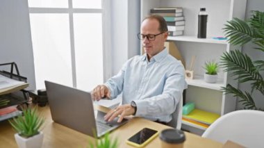 Endişeli orta yaşlı adam öksürüyor; çalışkan iş adamı ofiste hastalıkla savaşıyor, korkusuz ve odaklanmış, güvenilir bilgisayarını kullanıyor.