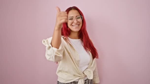 自信に満ちた楽しい若い赤毛の女性は シックな孤立したピンクの背景の上にクールな サインを点滅させます — ストック動画