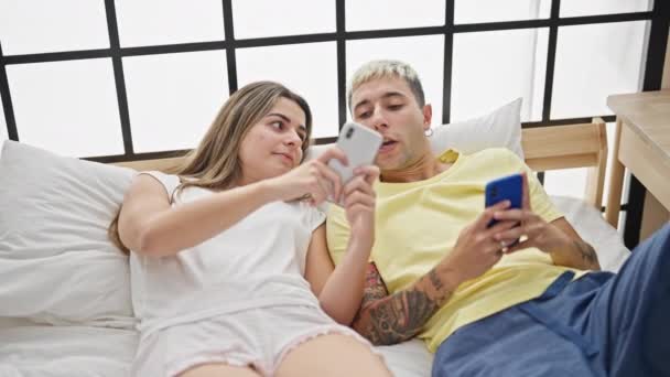 Mooi Paar Met Behulp Van Smartphones Liggend Bed Glimlachen Slaapkamer — Stockvideo