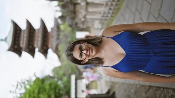 眼鏡付きの美しいヒップラティナ 彼女の目に輝く喜び 穏やかな上野公園の寺院で自信を持って歩いています カメラは東京のアジアの空の下で前進する彼女の陽気な笑顔をキャプチャします — ストック動画