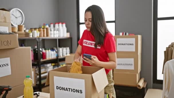 Giovane Volontaria Ispanica Laboriosa Controllando Magnificamente Donazioni Vestiti Nel Pacchetto — Video Stock
