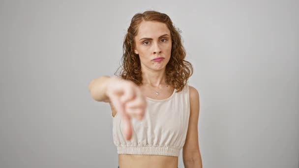 一个惊愕的年轻女子 孤身一人站在一个白色的背景下 描绘了一个负面的拇指垂下的姿势 她生气的脸和不高兴的表情显示出公然的不赞成 — 图库视频影像